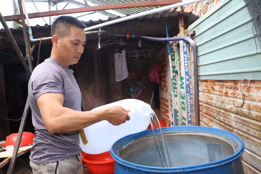 Mỗi ngày, anh Trần Văn Quyến phải đi xách nước cách nhà cả 1 km để về phục vụ cho kinh doanh, sinh hoạt. Ảnh: Quang Tấn