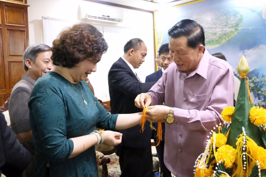 Tỉnh trưởng tỉnh Attapeu thực hiện nghi lễ buộc chỉ tay trong ngày Tết cổ truyền của đất nước Lào để cầu điều may mắn cho các thành viên trong đoàn công tác của tỉnh Gia Lai. Ảnh: Q.T