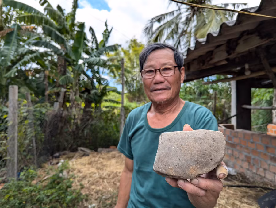 Ông Nguyễn Văn Quảng và hòn đá mài từng được người dân Tân Lập dùng trong quá khứ. Ảnh: N.Q.T