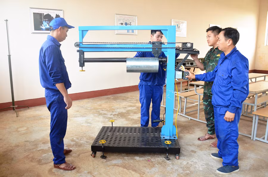 Thượng úy Nguyễn Đạt Dưỡng (bìa phải) hướng dẫn đồng nghiệp sử dụng thiết bị cán, gập định hình ống xả xe ô tô. Ảnh: Vĩnh Hoàng Thượng úy Nguyễn Đạt Dưỡng (bìa phải) hướng dẫn đồng nghiệp sử dụng thiết bị cán, gập định hình ống xả xe ô tô. Ảnh: Vĩnh Hoàng