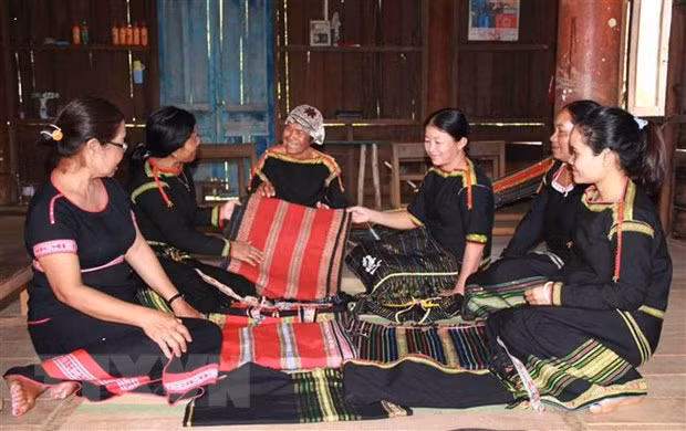 Bà Aduôi H’Noai, người có thâm niên dệt thổ cẩm lâu nhất ở buôn K’bu, trao đổi cách dệt thổ cẩm đối với phụ nữ Ê đê trong buôn K’bu, xã Hòa Khánh, thành phố Buôn Ma Thuột. (Ảnh: Phạm Cường/TTXVN)