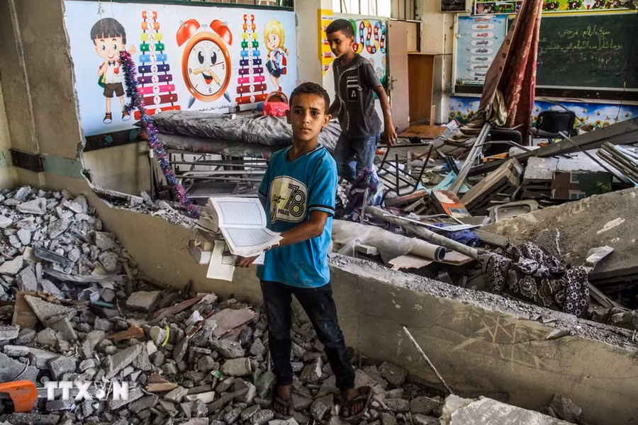 Trẻ em bên đống đổ nát của trường học bị trúng không kích của Israel tại thành phố Gaza ngày 25/6. (Ảnh: THX/TTXVN)
