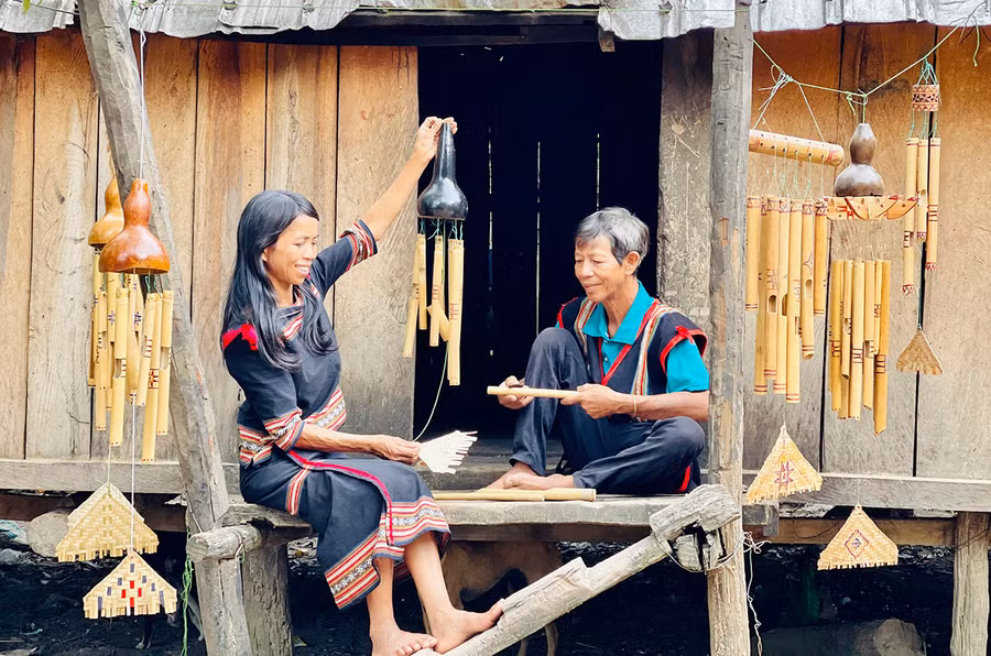Ông Byơh và con gái bên những chiếc chuông gió do mình chế tác. Ảnh: T.D