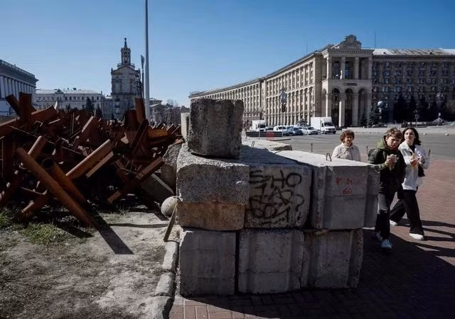 Người dân đi ngang công sự chống tăng tại Kyiv ngày 27.3. ẢNH: REUTERS