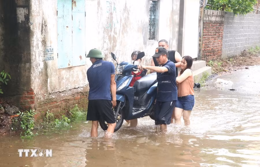 Người dân phường Lam Sơn, thành phố Hưng Yên di chuyển phương tiện đến nơi an toàn để tránh nước dâng cao. (Ảnh: Đinh Văn Nhiều/TTXVN)
