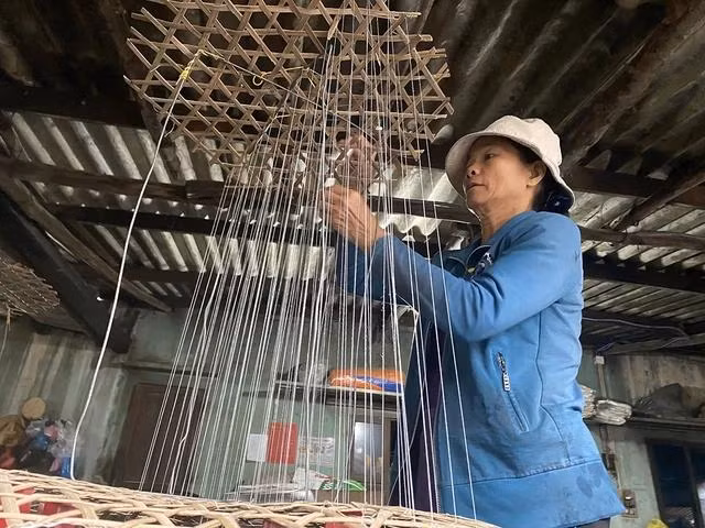 Bà Bùi Thị Anh Tuấn đang làm công đoạn luồn chỉ tạo khung, những sợi chỉ này đóng vai trò rất quan trọng trong công đoạn làm đường phèn. Ảnh: HẢI PHONG