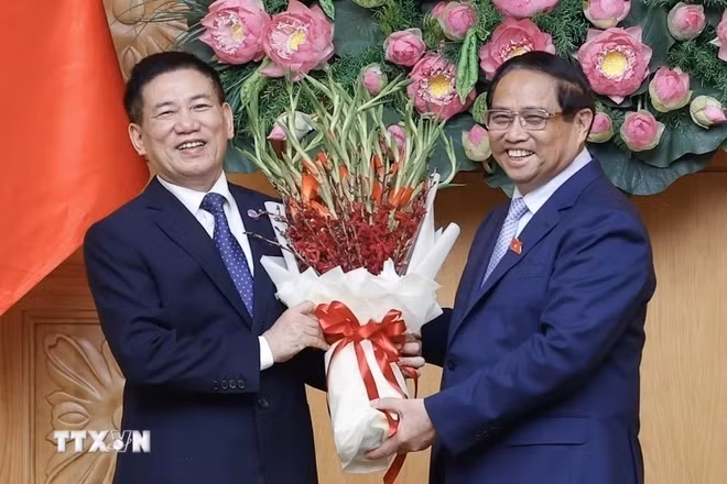 Thủ tướng Phạm Minh Chính tặng hoa chúc mừng tân Phó Thủ tướng Hồ Đức Phớc. (Ảnh: Dương Giang/TTXVN)