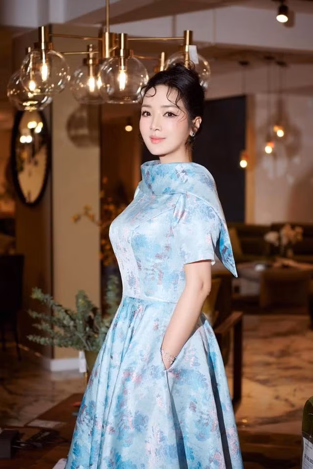 Khá chuộng họa tiết chìm và vẫn ưu tiên tông xanh, chiếc đầm xòe màu xanh dương có độ sáng bóng nhất định - là "chìa khóa" để nàng hậu trở nên rực rỡ và nổi bật hơn. Ảnh FACEBOOK NV Khá chuộng họa tiết chìm và vẫn ưu tiên tông xanh, chiếc đầm xòe màu xanh dương có độ sáng bóng nhất định - là "chìa khóa" để nàng hậu trở nên rực rỡ và nổi bật hơn. Ảnh FACEBOOK NV