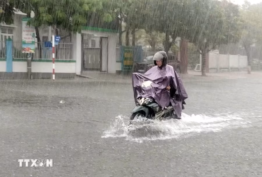 Tuyến đường ở thành phố Tam Kỳ bị ngập nước khiến người và phương tiện lưu thông rất khó khăn. (Ảnh: Trịnh Bang Nhiệm/TTXVN)