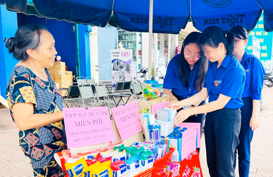 Bà Trần Thị Lý (bìa trái) hỗ trợ dụng cụ học tập, nước uống miễn phí cho các thí sinh trong kỳ thi tốt nghiệp THPT năm 2023. Ảnh: Phan Lài