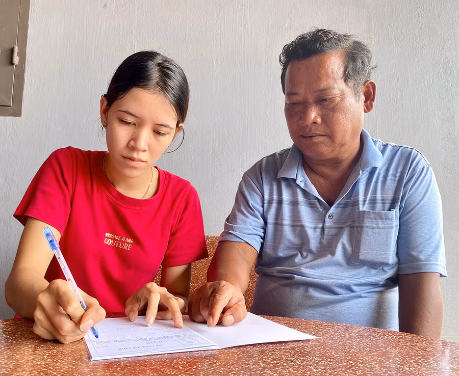 Ông Y Băn-Phó Bí thư Chi bộ làng Thung Dôr (xã An Phú) hướng dẫn chị H'Len viết lý lịch xin vào Đảng. Ảnh: Mộc Trà