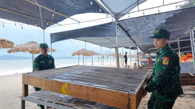 Các chiến sĩ đồn Biên phòng Cô Tô hỗ trợ người dân thu dọn tài sản, chằng chống hàng quán kinh doanh trên bãi biển
