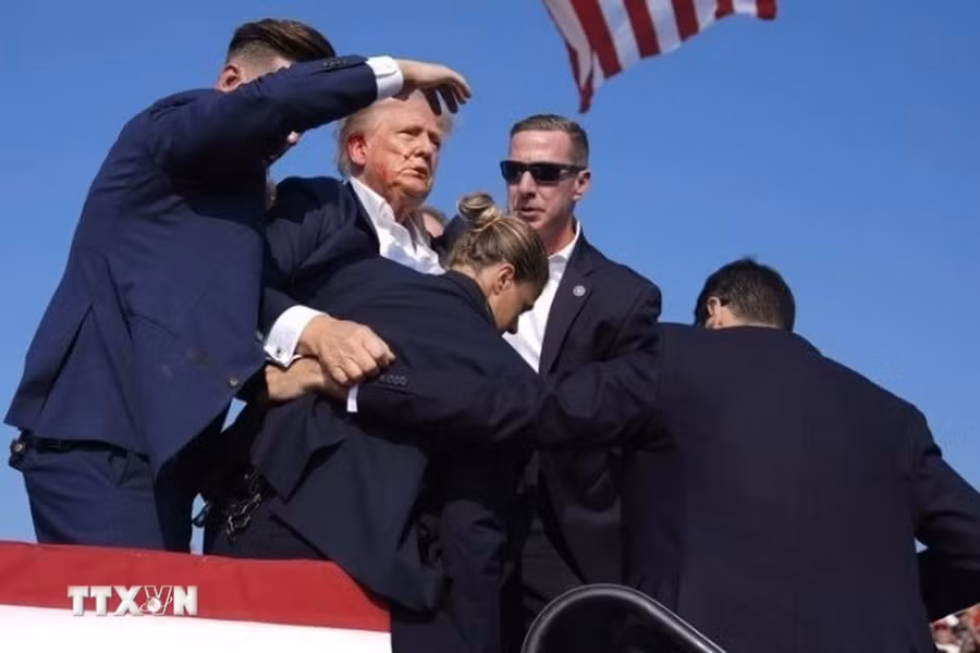 Cựu Tổng thống Donald Trump được mật vụ Mỹ hộ tống rời khỏi bục diễn thuyết trong cuộc vận động tranh cử ở thành phố Butler, bang Pennsylvania sau khi xảy ra vụ nổ súng, ngày 13/7. (Ảnh: THX/TTXVN') Cựu Tổng thống Donald Trump được mật vụ Mỹ hộ tống rời khỏi bục diễn thuyết trong cuộc vận động tranh cử ở thành phố Butler, bang Pennsylvania sau khi xảy ra vụ nổ súng, ngày 13/7. (Ảnh: THX/TTXVN')