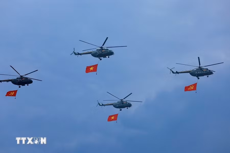 Máy bay trực thăng mang cờ Đảng, cờ Tổ quốc bay qua Lễ đài. (Ảnh: Dương Giang/TTXVN)