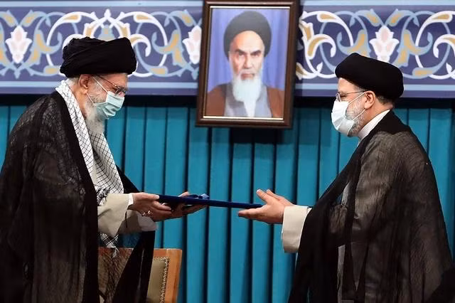 Lãnh tụ tối cao Ayatollah Ali Khamenei (trái) tại lễ nhậm chức của Tổng thống Ebrahim Raisi ngày 3.8.2021. Đằng sau là chân dung của cố Lãnh tụ tối cao Ayatollah Ruhollah Khomeini. Ảnh AFP