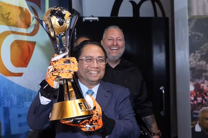 Thủ tướng Phạm Minh Chính nâng cúp vô địch FIFA Club World Cup 2012 của CLB Corinthians và đeo đôi găng tay của "người gác đền" - thủ môn Cassio, người đạt danh hiệu Quả bóng vàng trong giải đấu này. Ảnh: VGP