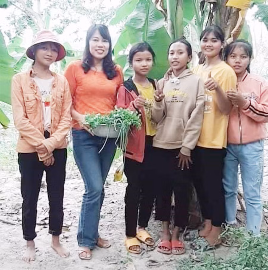 Tác giả (thứ 2 từ trái sang) trong một lần về làng thăm học sinh. Ảnh: Mai Hương