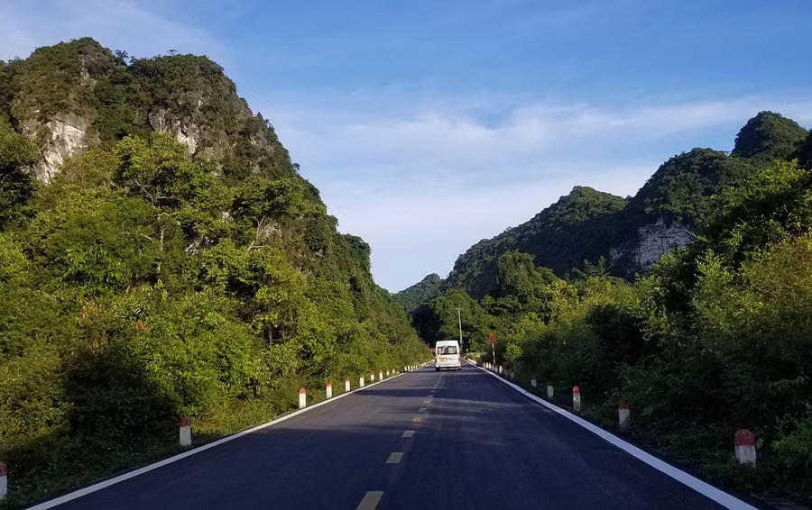 Hun hút hai bên đường là rừng cây nhiệt đới và dãy núi đá vôi trùng điệp. Ảnh: GIANG LINH