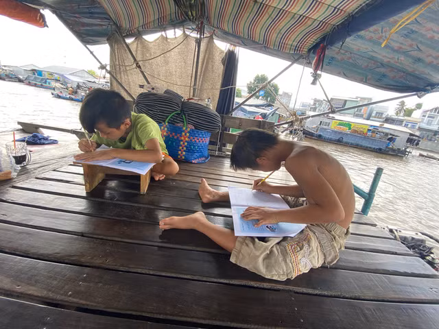 Xệ và Bẹt tập viết trên ghe. Ảnh: Lê Vân