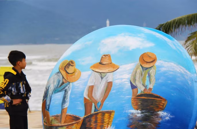 Một du khách nhỏ tuổi đang chiêm ngưỡng bức họa về người ngư dân Đà Nẵng