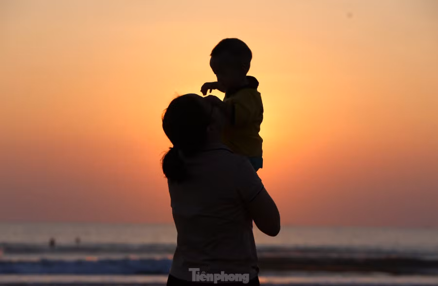 “Lần đầu tiên cùng gia đình đến biển Xuân Thành, tôi cố gắng thức dậy sớm để ngắm bình minh, cảm nhận không khí tuyệt vời nhất”, Hoài Thường (17 tuổi, trú TP Hà Tĩnh) chia sẻ. Dưới ánh mặt trời ló rạng, người mẹ trao nụ hôn và tình yêu thương đến con trai.