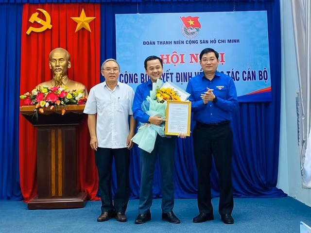 Anh Bùi Minh Tuấn (bìa phải), ông Lê Đình Giám (bìa trái) trao quyết định công nhận và tặng hoa chúc mừng anh Nguyễn Thành Trung. Ảnh: N.Đ