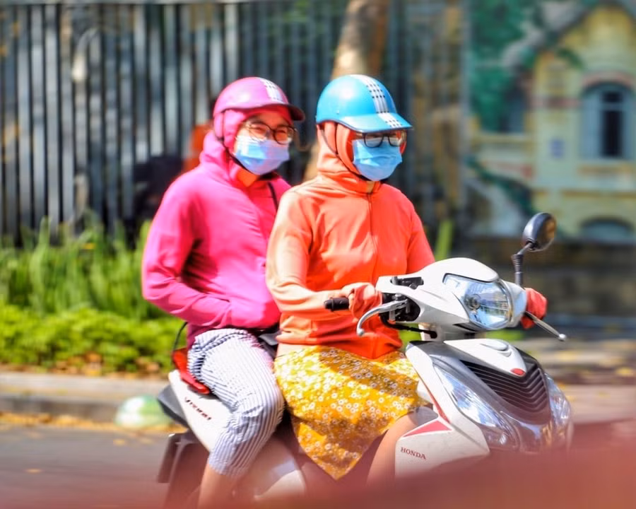 Để tránh sốc nhiệt, người ra đường luôn mặc áo chống nắng. (Ảnh: Tuấn Đức/TTXVN)