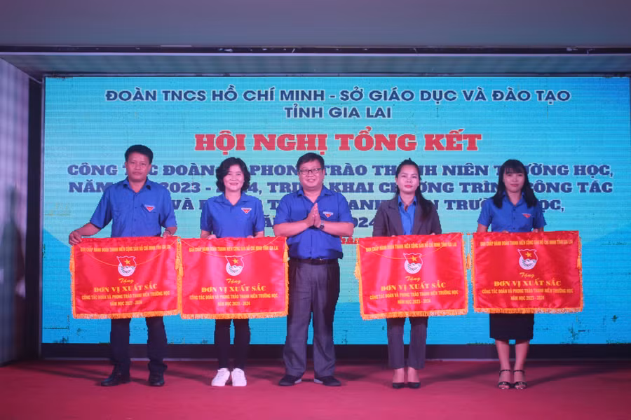 Anh Nguyễn Chí Hiếu (ở giữa)-Phó Bí thư Tỉnh Đoàn tặng cờ thi đua của Ban Chấp hành Tỉnh Đoàn cho các tập thể có thành tích xuất sắc trong công tác Đoàn trường học. Ảnh: P.L