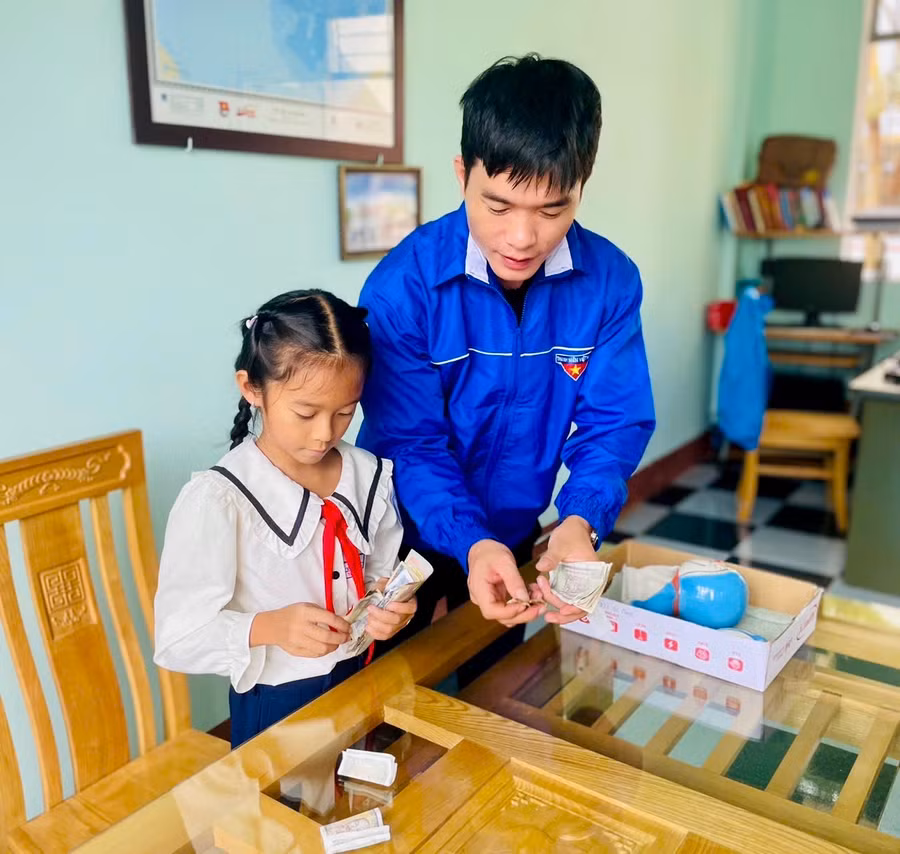 Em Hoàng Thụy Khanh (bìa trái) đập heo đất ủng hộ các bạn thiếu nhi bị ảnh hưởng do bão lũ. Ảnh: M.N