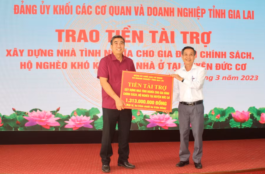 Phó Bí thư Đảng ủy Khối Huỳnh Tấn Đoan (bìa phải) trao bảng tượng trưng tiền tài trợ cho ông Vũ Mạnh Định-Chủ tịch UBND huyện Đức Cơ. Ảnh: Phan Lài