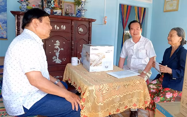 Chủ tịch Hội đồng hương Bình Định Đỗ Thanh Hùng (ngồi giữa) trong buổi bàn giao nhà tình nghĩa cho hộ nghèo ở phường Tam Quan Nam, TX Hoài Nhơn, chi phí xây nhà do cá nhân ông hỗ trợ. Ảnh: NGỌC NHUẬN