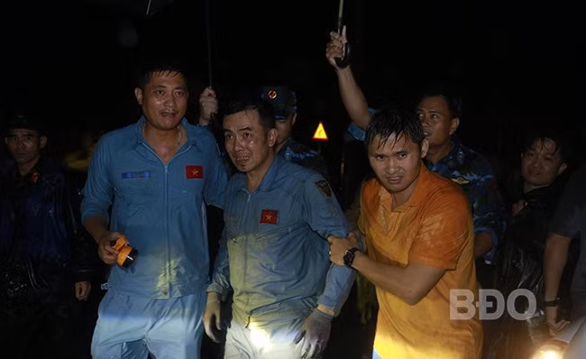 Thượng tá, phi công Nguyễn Hồng Quân (giữa) được lực lượng cứu nạn đưa ra khỏi rừng. Ảnh: H.P