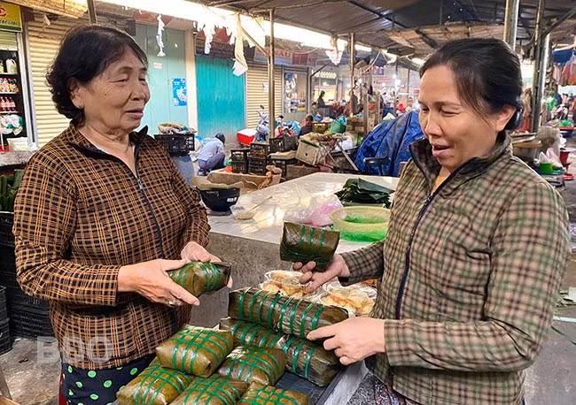 Ở tuổi 82, bà Trần Thị Thao (thị trấn Diêu Trì, huyện Tuy Phước, bên trái) vẫn gắn bó với nghề gói bánh chưng và sạp bánh chưng ở chợ Diêu Trì.