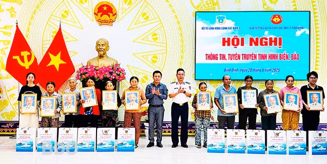 Lãnh đạo Bộ Tư lệnh Vùng Cảnh sát biển 2 và TX Hoài Nhơn tặng ảnh Bác Hồ và quà cho các hộ gia đình. Ảnh: D.Đ