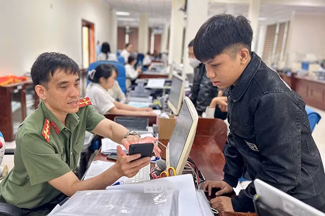 Cán bộ CA hướng dẫn công dân giải quyết thủ tục hành chính trên Cổng Dịch vụ công Quốc gia. Ảnh: KIỀU ANH