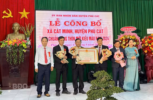 Lãnh đạo huyện Phù Cát trao bằng công nhận xã Cát Minh đạt chuẩn NTM kiểu mẫu của UBND tỉnh cho lãnh đạo xã. Ảnh: Trường Giang.
