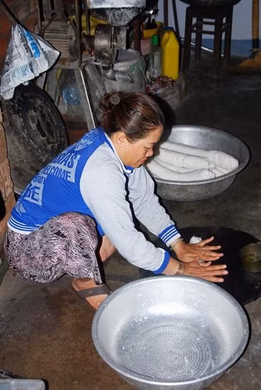 Bột được lăn thành cây trước khi đưa vào khuôn ép.