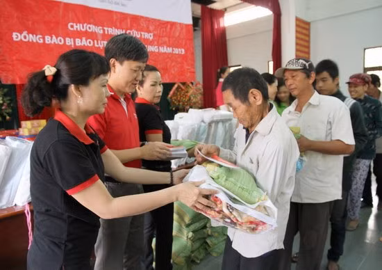 Ông Trần Đình Quân- Phó Tổng giám đốc điều hành Công ty Dai-ichi Life Việt Nam (áo đỏ) tặng quà cho các hộ gia đình ở phường Nhơn Phú.