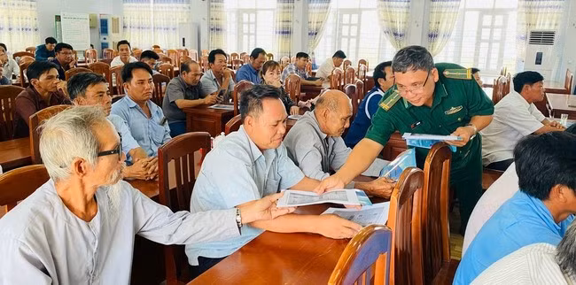 Cán bộ đồn Biên phòng Mỹ An cấp phát tờ rơi tuyên truyền cho ngư dân.