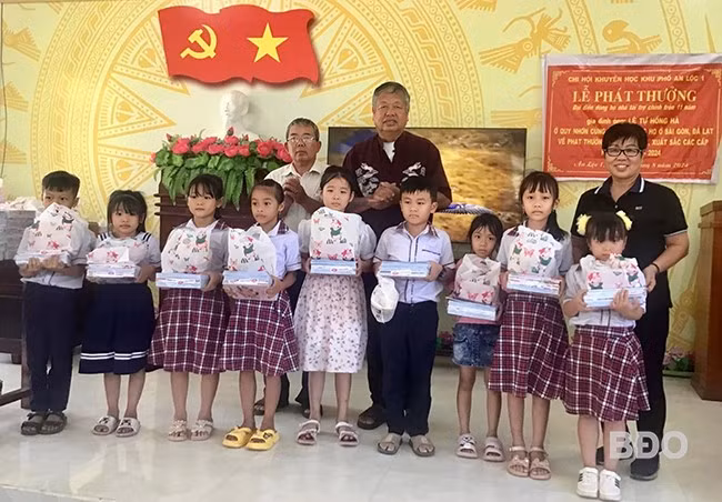 Bà Tuyết (bìa phải) cùng chồng (giữa) trao học bổng cho học sinh vượt khó học giỏi ở phường Hoài Thanh (TX Hoài Nhơn). Ảnh: NVCC