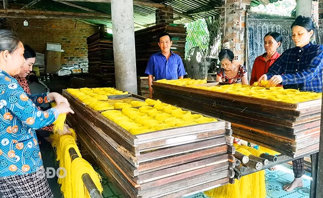 Anh Lâm Hoàng Vũ hướng dẫn người lao động cho bún gạo sợi vàng vào khuôn trước khi mang đi phơi. Ảnh: XUÂN THỨC