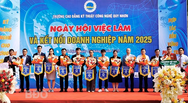 Lãnh đạo Trường CĐ Kỹ thuật Công nghệ Quy Nhơn tặng hoa, cờ lưu niệm cho các DN tham gia ngày hội. Ảnh: N.M.