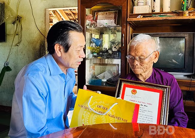 Phó Chủ tịch Thường trực HĐND tỉnh Đoàn Văn Phi tặng quà, thiếp mừng thọ của Chủ tịch nước cho cụ Mai Thị Hảo. Ảnh: D.Đ