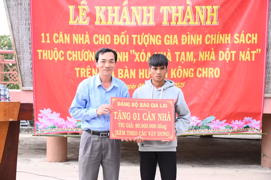 Phó Tổng Biên tập Báo Gia Lai Lương Văn Danh (bìa trái) trao bảng tượng trưng hỗ trợ xây dựng 1 căn nhà ở cho hộ nghèo ở huyện Kông Chro. Ảnh: Đ.T
