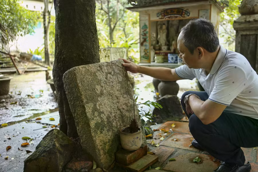 Phóng viên Thanh Niên bên phiến đá cổ tại Viên Thông Am có ghi chữ Hán nhưng đã phai nhòa theo thời gian