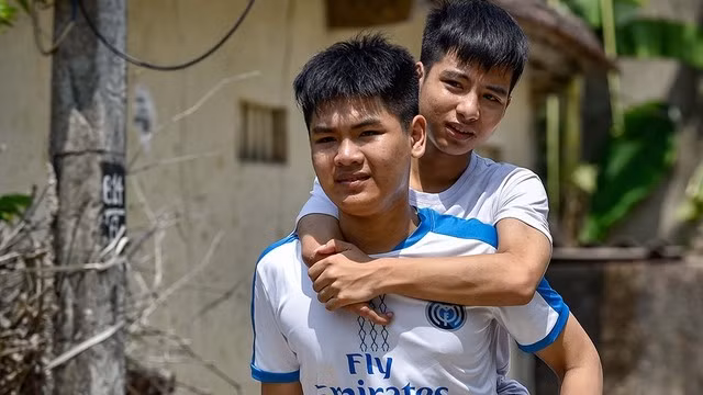 Ngô Văn Hiếu cõng Nguyễn Tất Minh khi cả hai còn theo học phổ thông. Ảnh: Phúc Ngư