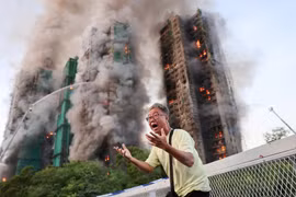 Một người đàn ông cầu xin giúp đỡ trong lúc ngọn lửa bao trùm cụm chung cư Wang Fuk Court. Ảnh: Reuters