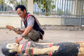 Nghệ nhân Nay Lâm hoàn thiện bức tượng gỗ người phụ nữ Jrai. Ảnh: V.C