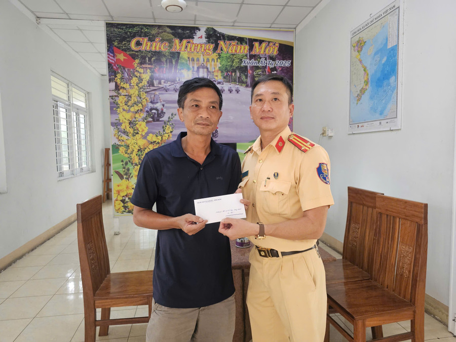 Trung tá Tô Hồng Phúc-Phó trạm trưởng Trạm CSGT Tuy Phước trao tiền hỗ trợ cho gia đình tài xế. Ảnh: ĐVCC canh-sat-giao-thong-giup-nan-nhan-xuat-huyet-nao.jpg