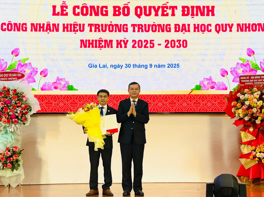 Thứ trưởng Bộ Giáo dục và Đào tạo Nguyễn Văn Phúc trao quyết định, tặng hoa chúc mừng PGS.TS. Đoàn Đức Tùng. Ảnh: T.D pgsts-doan-duc-tung-hieu-truong-dh-quy-nhon.jpg